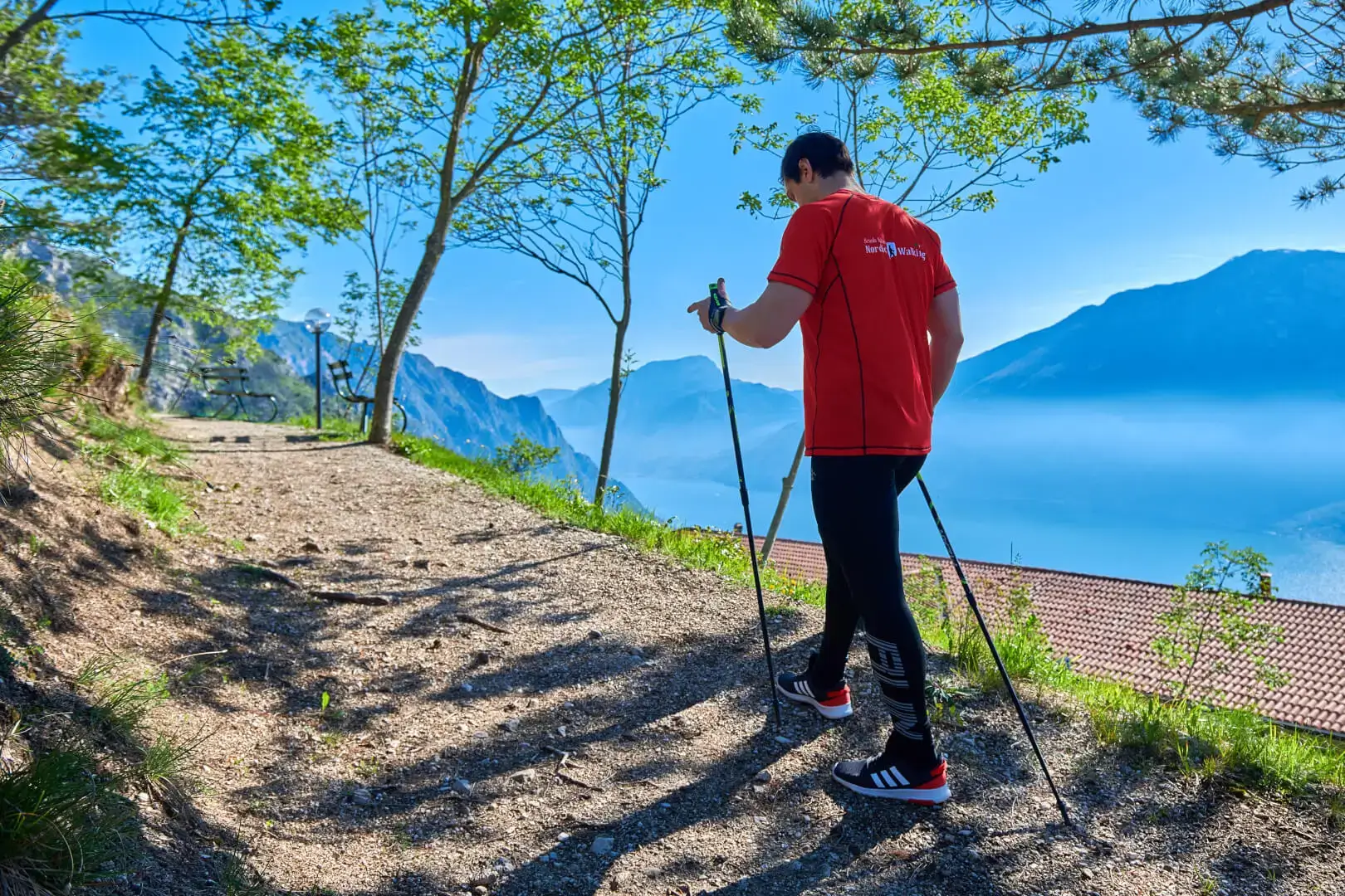 Escursionista su sentiero montano con vista lago.