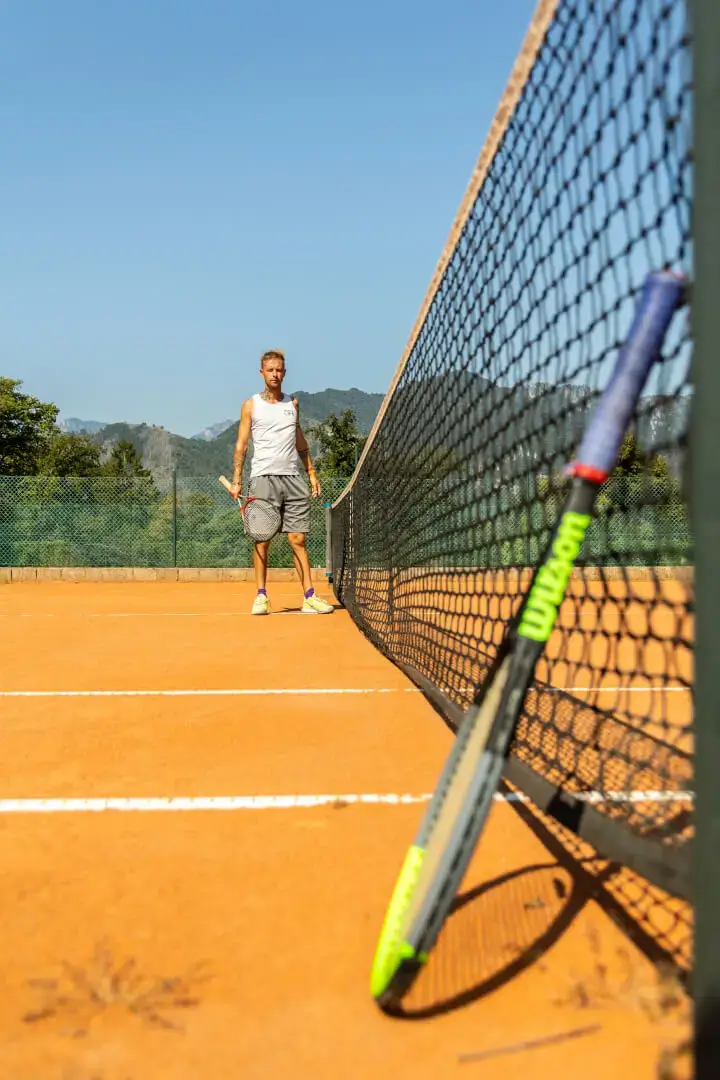 Giocatore di tennis su campo in terra rossa.
