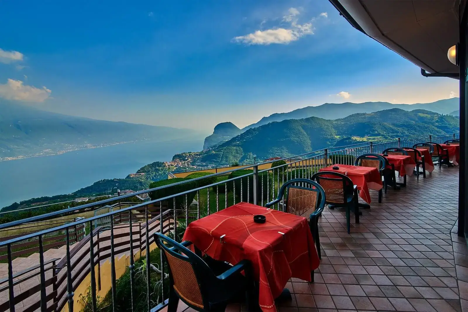 Terrazza panoramica sul lago con tavoli rossi.