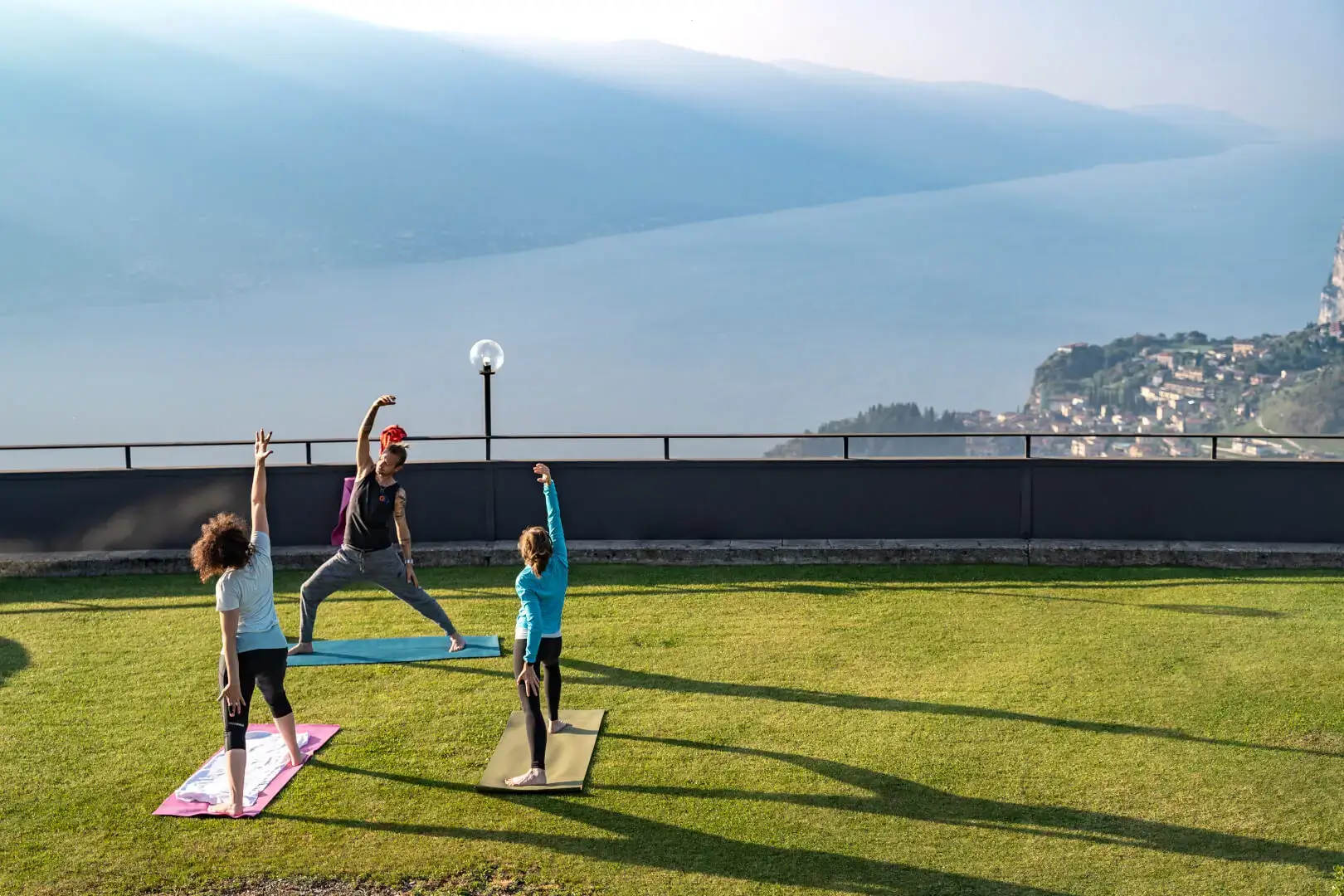 Famiglia fa yoga all'aperto con vista lago.